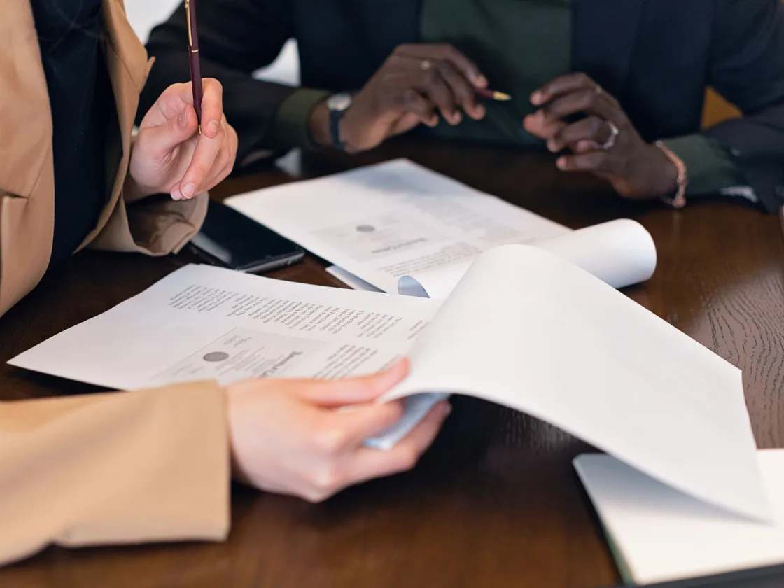 Two people going through printed documents across a desk