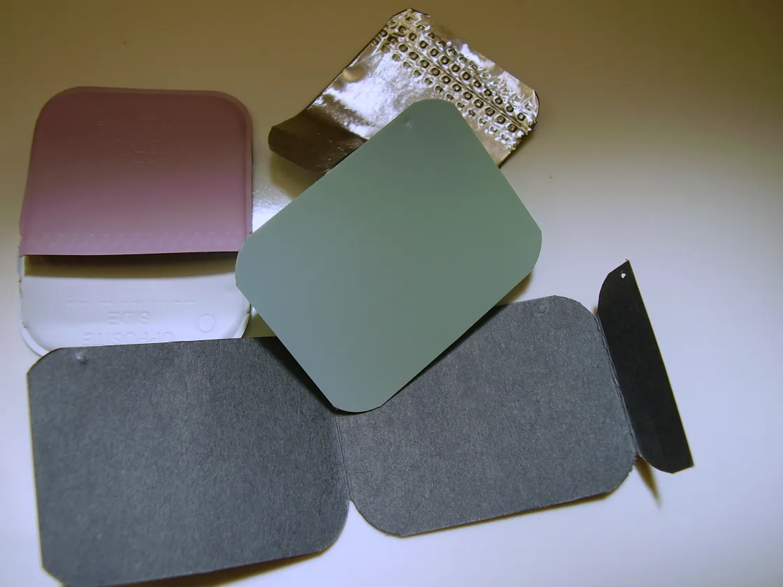 One dental X-ray film packet opened out: plastic housing, lead foil, film and paper