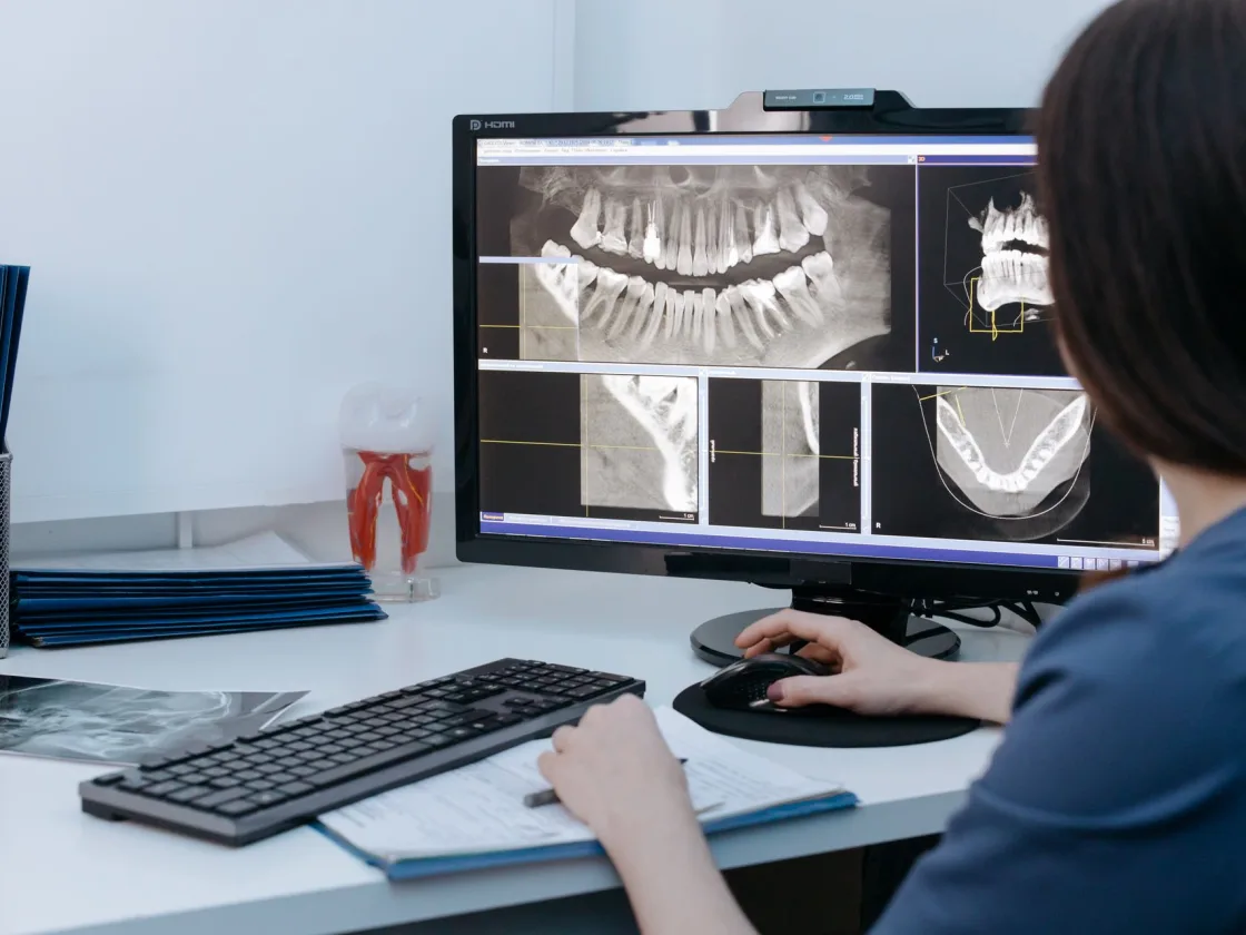 A clinician reviewing panoramic and cross-sectional views at a practice workstation